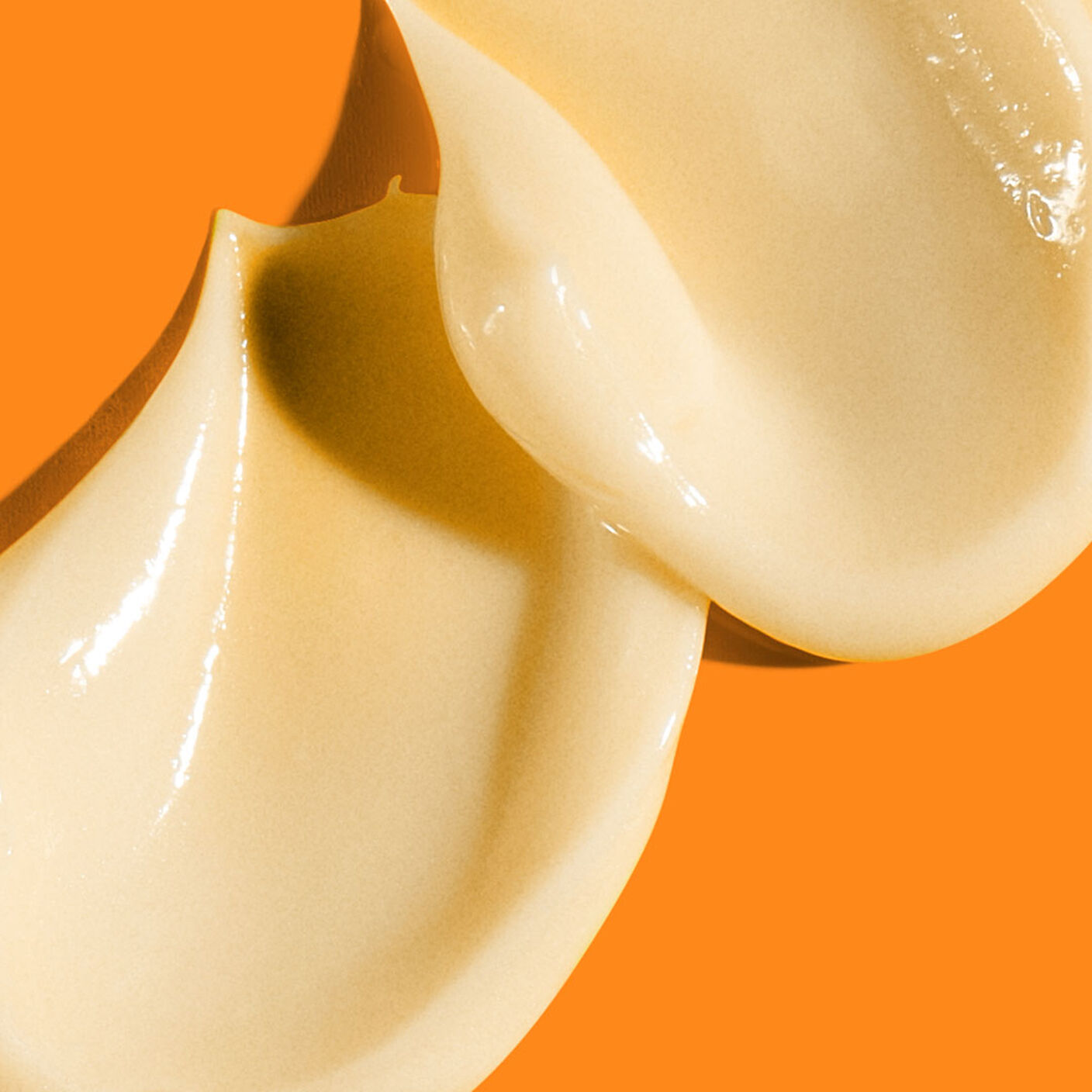 2 La crème contour des yeux multivitaminée C-Tango épaisse s'étale sur un fond orange foncé.