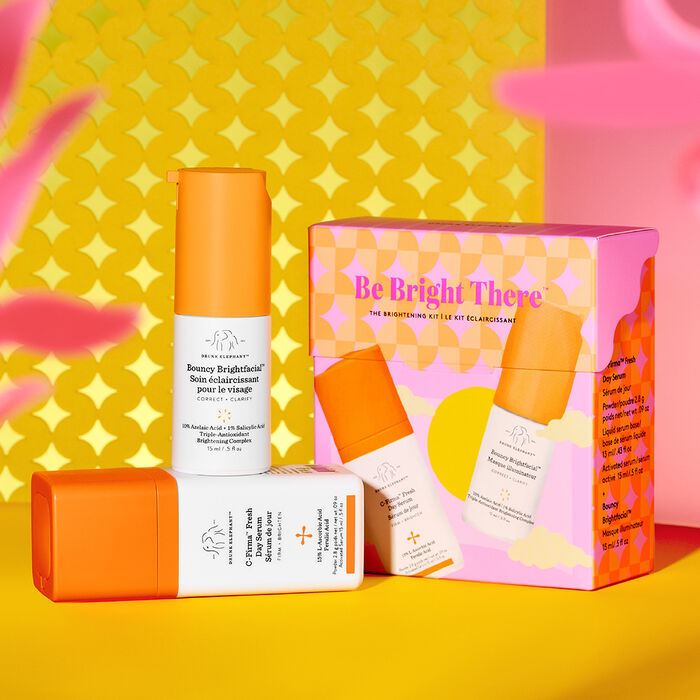 Bouncy Brightfacial and C-Firma Fresh standing on top of each other in front of kit packaging with golden yellow and pink graphic background